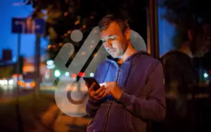 Man looking at Phone at Bus Stop during the Night